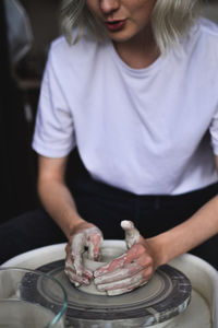 Midsection of woman making pottery at workshop