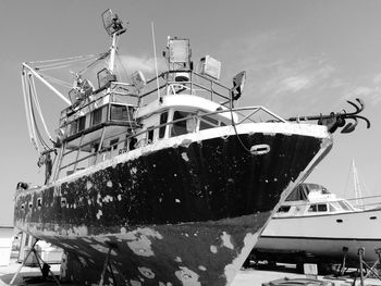 Rusty ship moored at harbor against sky