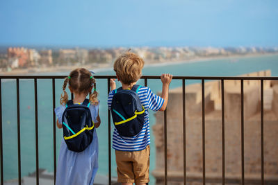 Rear view of mother and daughter standing against sky