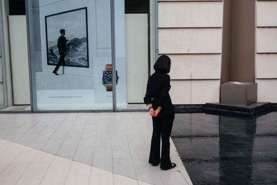 Rear view of woman walking by wall