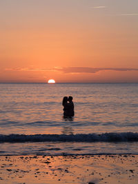 Silhouette man on beach against sky during sunset