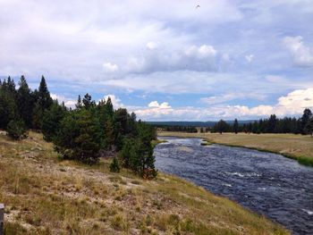 Scenic view of river against cloudy sky