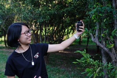 Girl holding camera lens in forest