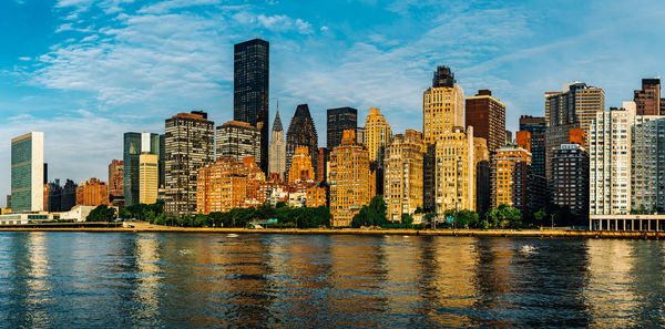 Sea by modern buildings against sky in city