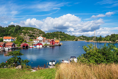 Houses by lake and buildings against sky