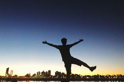 Silhouette man with arms outstretched against sky during sunset