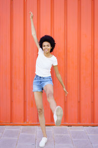 Full length of young woman standing against yellow wall