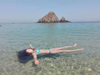 Young woman floating on sea at beach