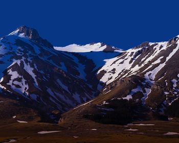 Scenic view of snowcapped mountains against clear blue sky