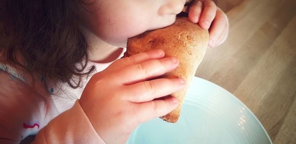 Midsection of girl eating food on table at home