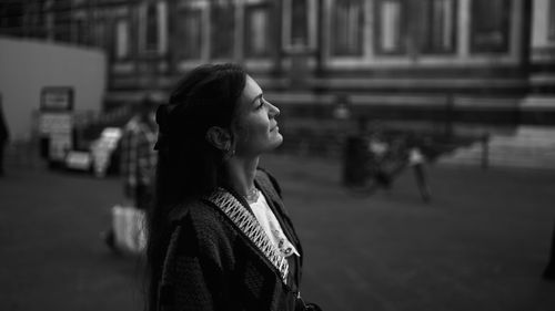 Side view of young woman looking away in city