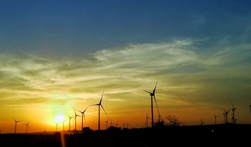 Silhouette of wind turbines at sunset