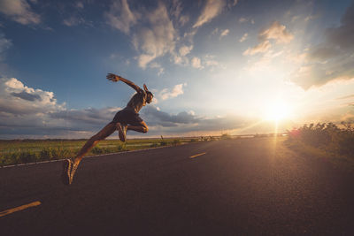 Man skateboarding on road against sky during sunset