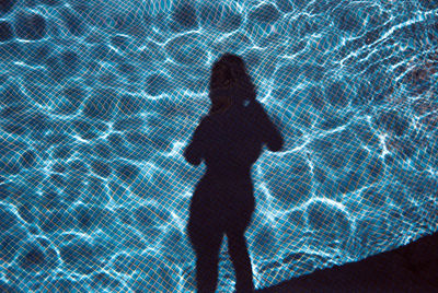 Rear view of silhouette woman standing by swimming pool