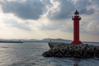 Lighthouse by sea against sky