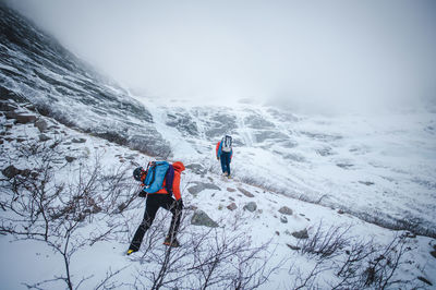 People on snowcapped mountain against sky