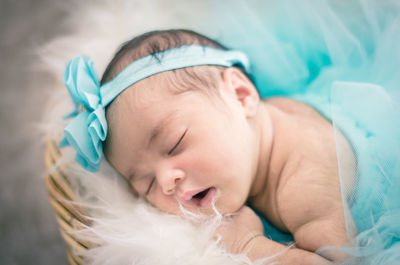 Close-up of baby girl sleeping in basket