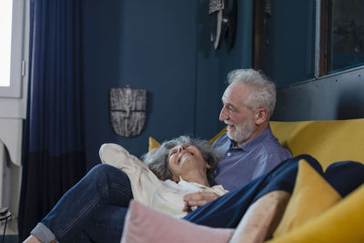 Happy senior couple resting on sofa at home