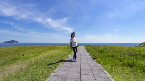 Rear view of woman walking on beach against sky