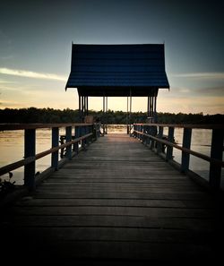 Pier over lake against sky during sunset