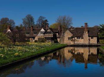 Houses by lake and buildings against clear blue sky