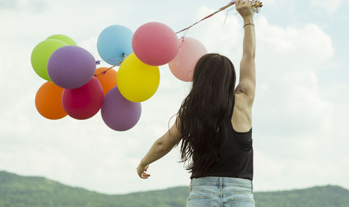 Low section of woman with balloons standing against sky