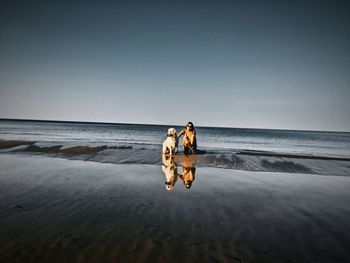 My two biggest love at baltic sea beach against clear sky