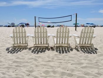 Chairs on beach against sky