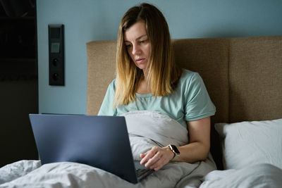 Woman lying in bed and using laptop