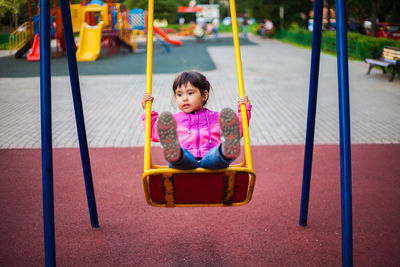 Cute girl swinging on swing in playground