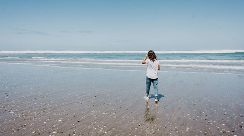 Full length of man standing on beach against sky