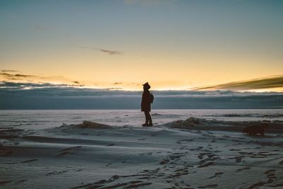 Man standing on field against sky during sunset