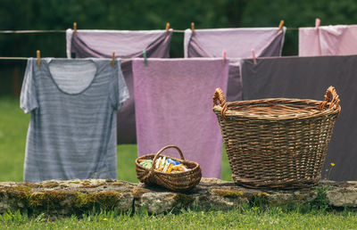 Wicker baskets for laundry and clothes pegs in front of a clothesline with clothes drying