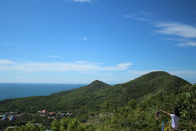 Scenic view of sea and mountains against blue sky