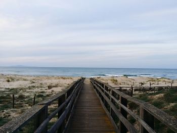 Boardwalk on beach against sky