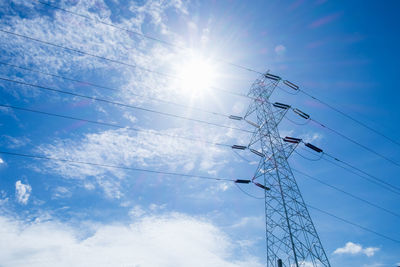 Low angle view of electricity pylon against blue sky