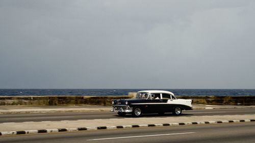 Car on road by sea against sky