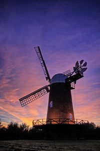 Silhouette of wind turbines in field