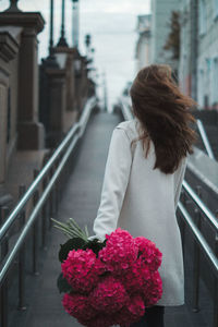 Rear view of woman with pink flowers on railing