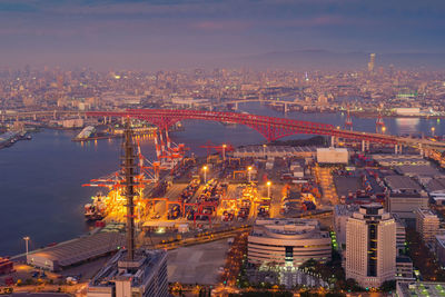 High angle view of illuminated buildings by river against sky