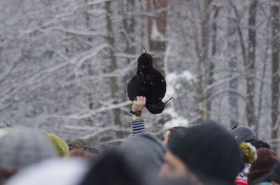 A man rising his arm above the croud with traditional russian ushanka, during maslenitsa festivities