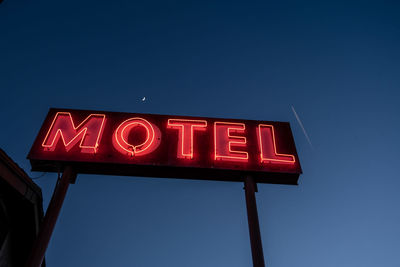 Low angle view of illuminated sign against blue sky