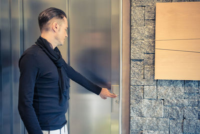 Man pressing elevator button in hotel