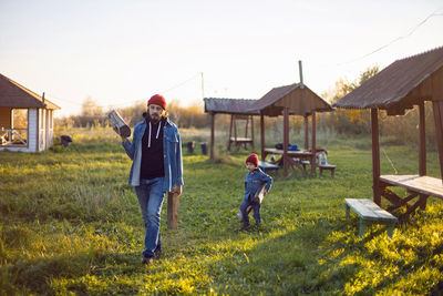 Father and son carry firewood outside in the evening in autumn at sunset in nature