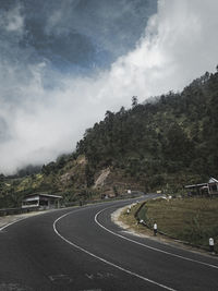 Road by trees against sky