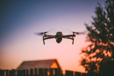 Low angle view of airplane flying against sky at sunset