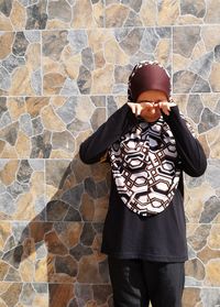 Man wearing sunglasses standing against brick wall