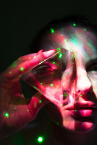 Close-up of hand holding illuminated light over black background