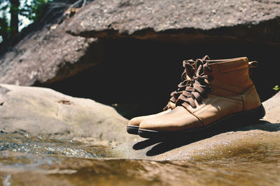 Close-up of shoes on rock by puddle