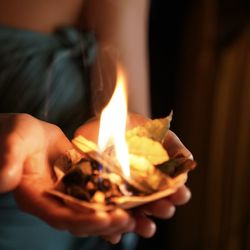 Close-up of hands holding burning candle